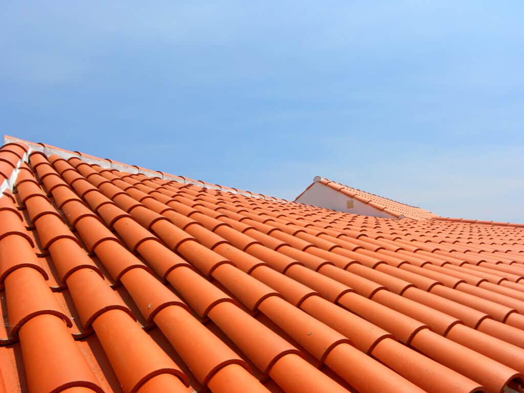 Red tile roof under blue sky. The photo is divided in half. One